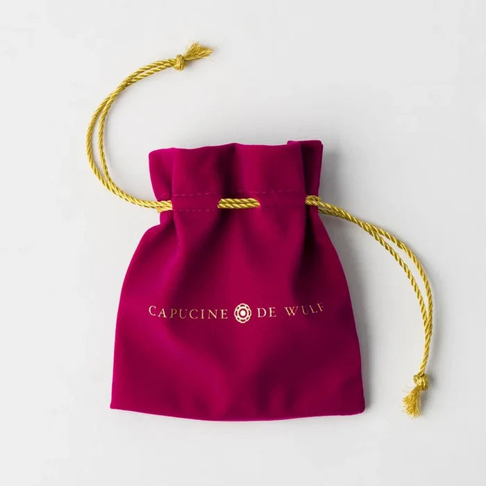 Red velvet drawstring bag with gold rope and 'Capucine de Wulf' branding.