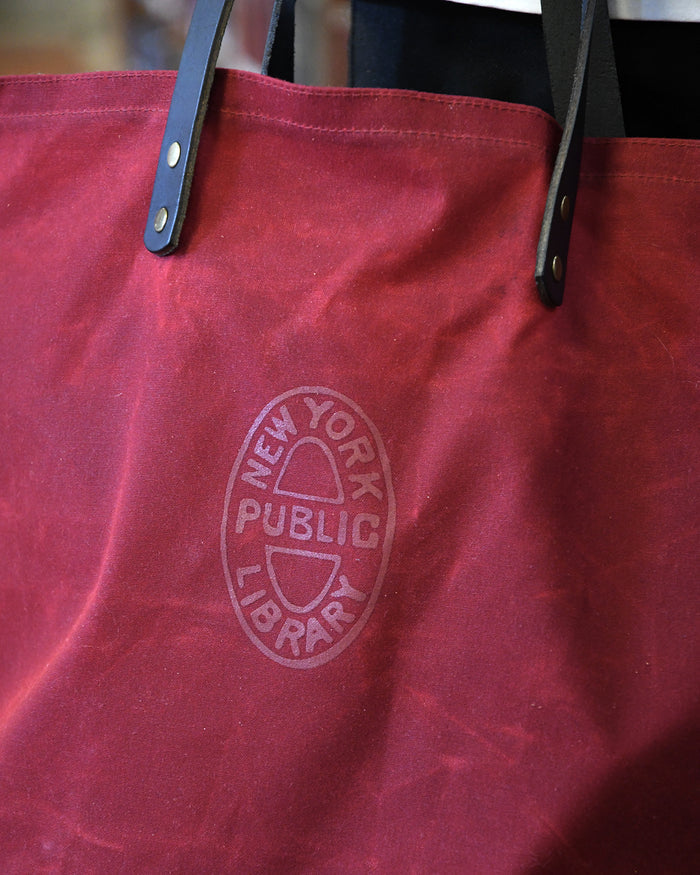 Red tote bag with a NYPL oval logo that reads: New York Public Library.