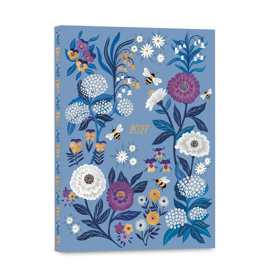 A 2027 floral illustrated desk calendar or planner with a dusty blue cover, featuring white, purple, yellow, and orange flowers, blue leaves, bumblebees, and the year '2027' in gold near the center.