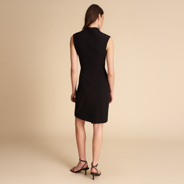 Woman wearing a black sleeveless dress on a beige background