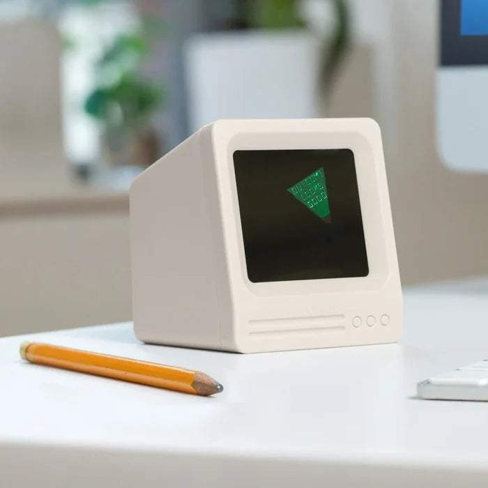 Eight ball-like game shaped as a Small computer monitor with a green triangle on a desk next to a pencil.