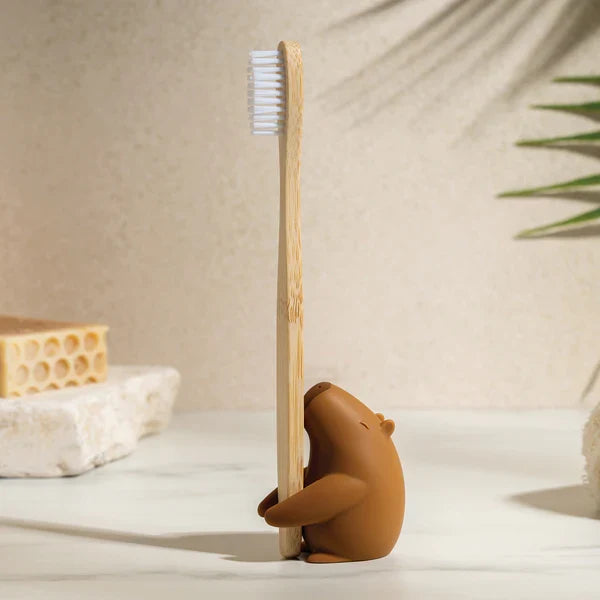 Bamboo toothbrush with a capybara-shaped holder on a neutral background