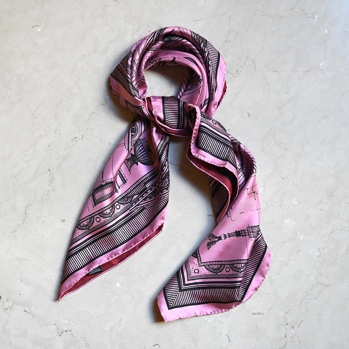 Pink and black patterned scarf on a light gray surface