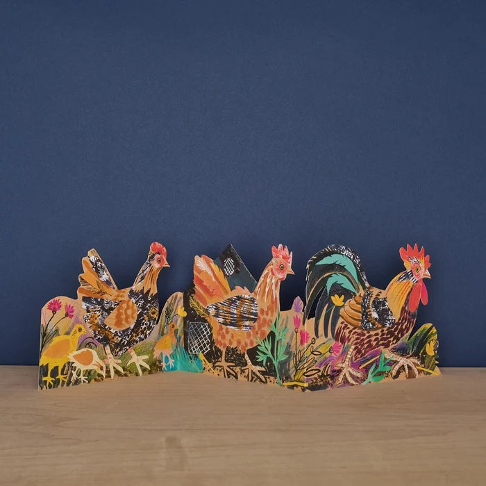A fully opened freestanding three-panel die-cut card displaying a colorful farmyard illustration with hens, chicks, and a rooster among wildflowers.
