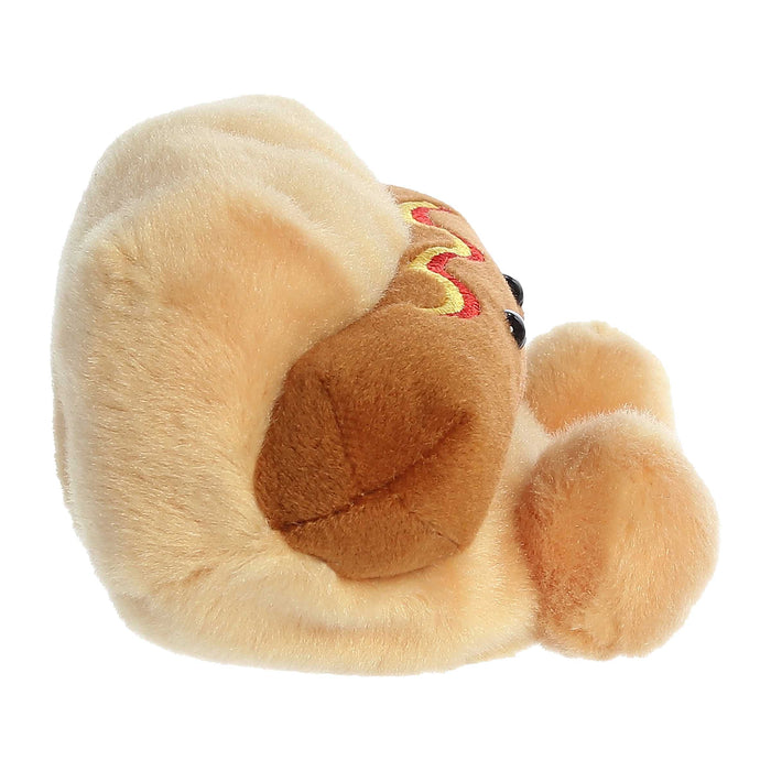 Plush toy resembling a hot dog with mustard and ketchup on a white background from a side angle.
