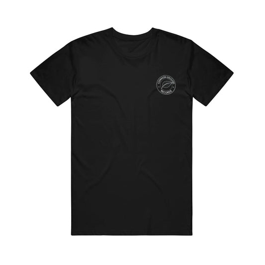 Common Ground Collective black short-sleeve t-shirt with a small white circular logo showing text and a guitar graphic on the upper left chest, displayed on a plain white background.
