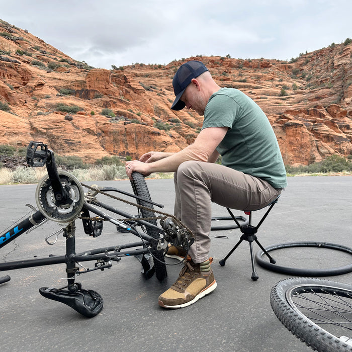 Man working on bike in the desert while sitting on stool