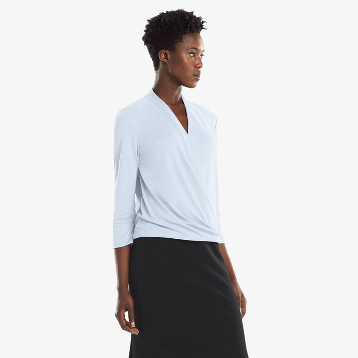 Side image of a woman standing wearing the Deneuve top in Oxford Blue