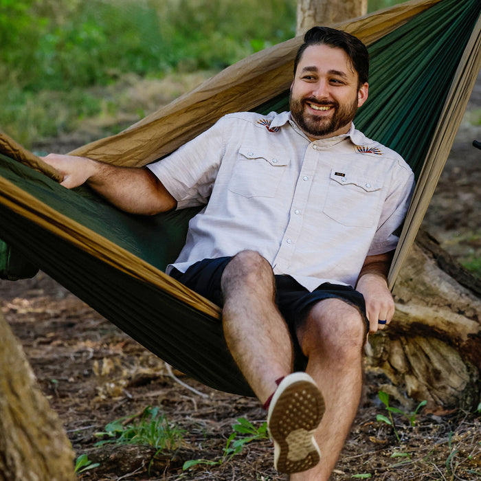 Man swinging in the double deluxe hammock in the forest with a howler brothers shirt