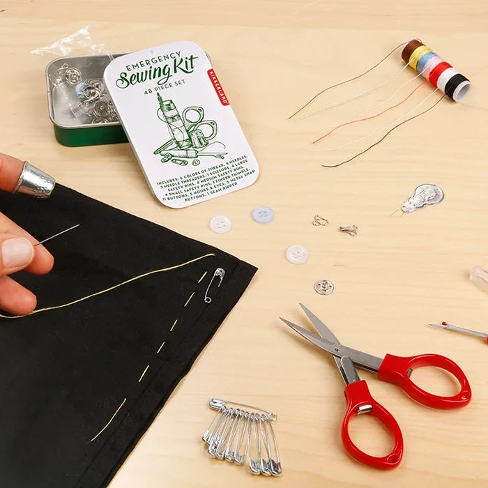 Emergency sewing kit with scissors, thread, and pins on a wooden surface