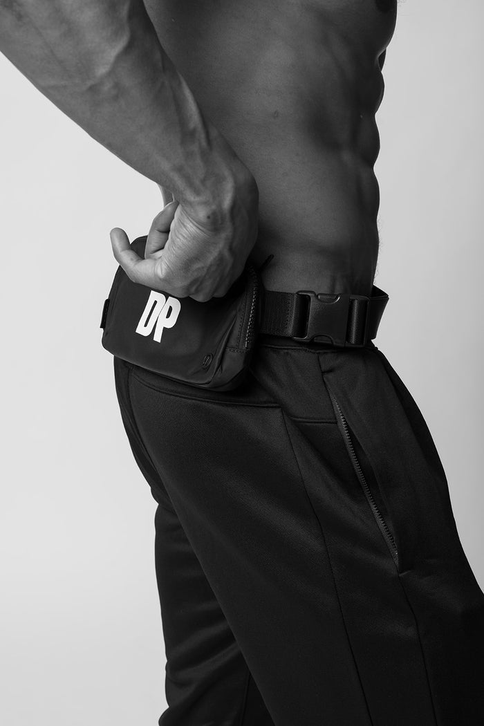 Man wearing Dogpound branded belt bag around waist with large, white DP logo
