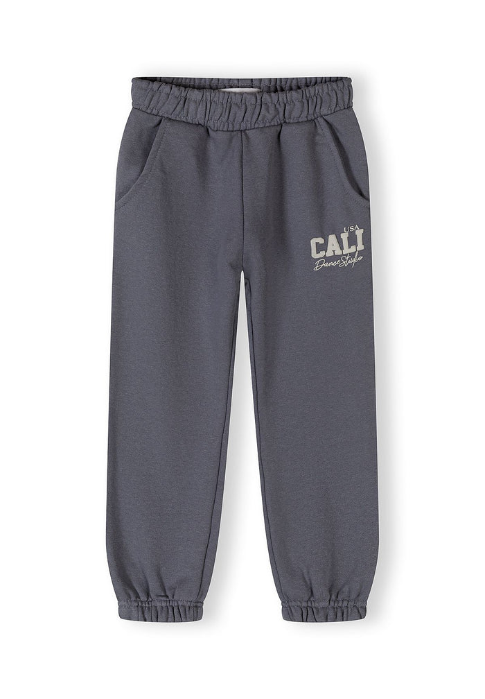 Detail of girls' tapered jogging trousers in blue-grey with elasticated waistband and side pockets.
