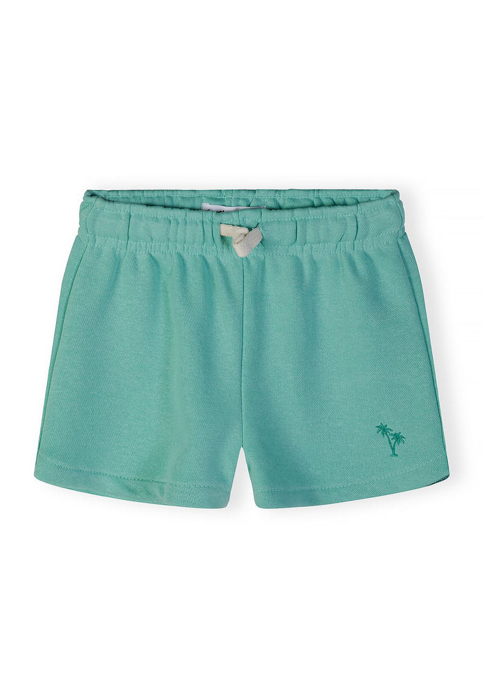 Detail of girls' green cotton blend shorts with elastic waistband and palm tree embroidery.