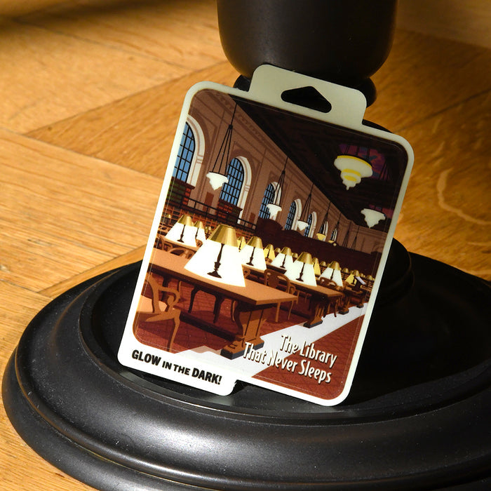 Glow in the dark sticker featuring the Rose Main Reading Room at night with all the lamps on. Text at the bottom right corner reads: The Library that never sleeps.