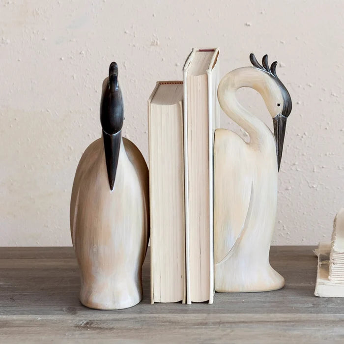 Decorative bird bookends on a wooden surface with a neutral background