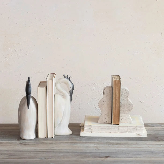 Decorative bookends shaped like herons on a wooden surface with a light background