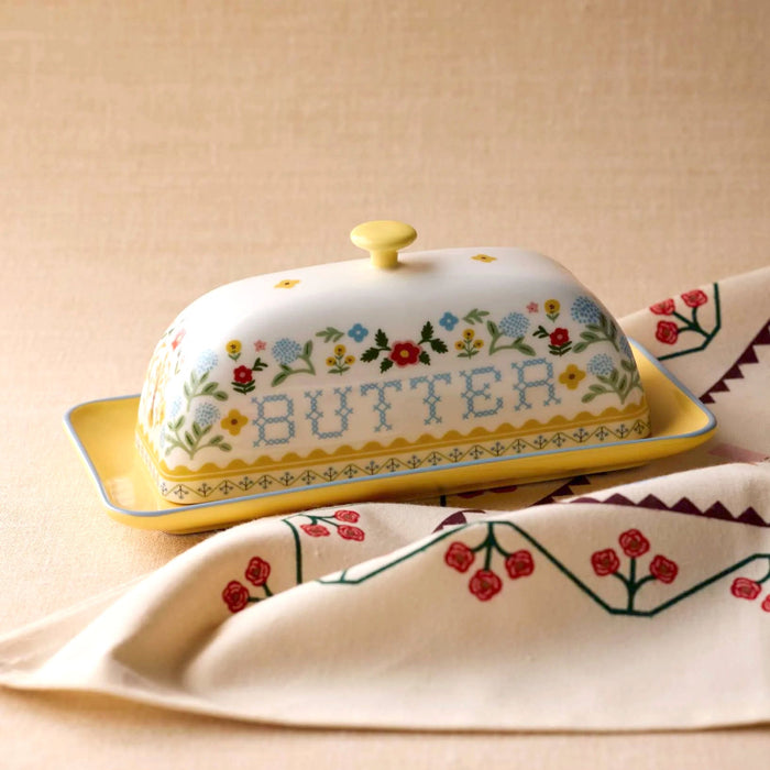 Decorative butter dish with floral patterns and 'BUTTER' text on a beige background