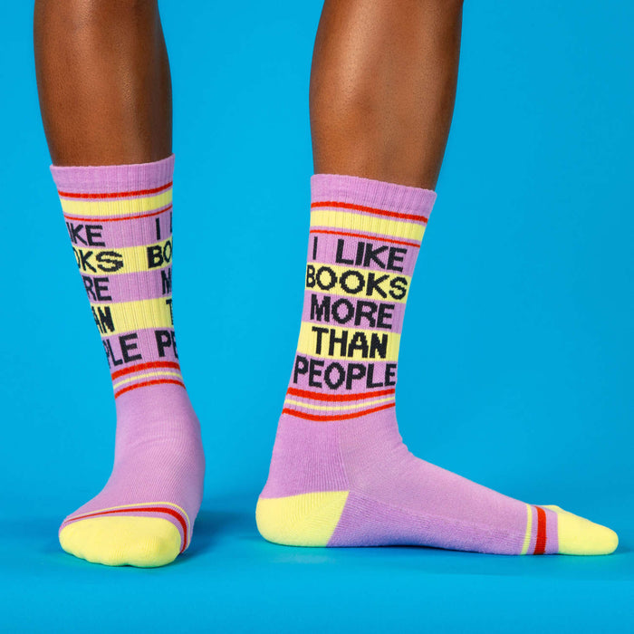Purple socks with text 'I LIKE BOOKS MORE THAN PEOPLE' on a blue background