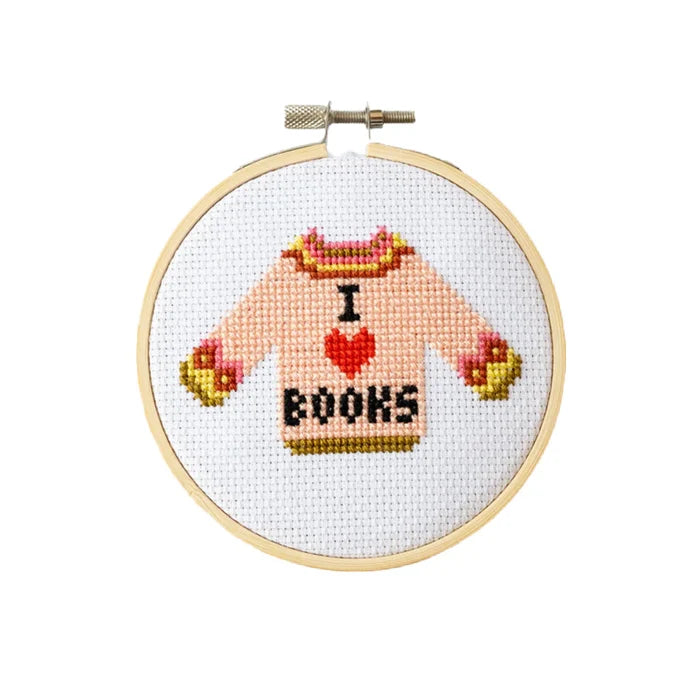 Cross-stitched design of a sweater with 'I ❤️ BOOKS' text in a wooden hoop.