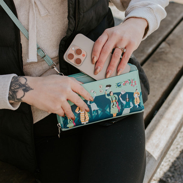 Person holding a phone over a floral-patterned wallet on a wooden surface