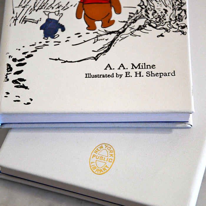 Book with illustrations of a baby pig and a dog, titled 'A. A. Milne' illustrated by E. H. Shepard, on a white surface.