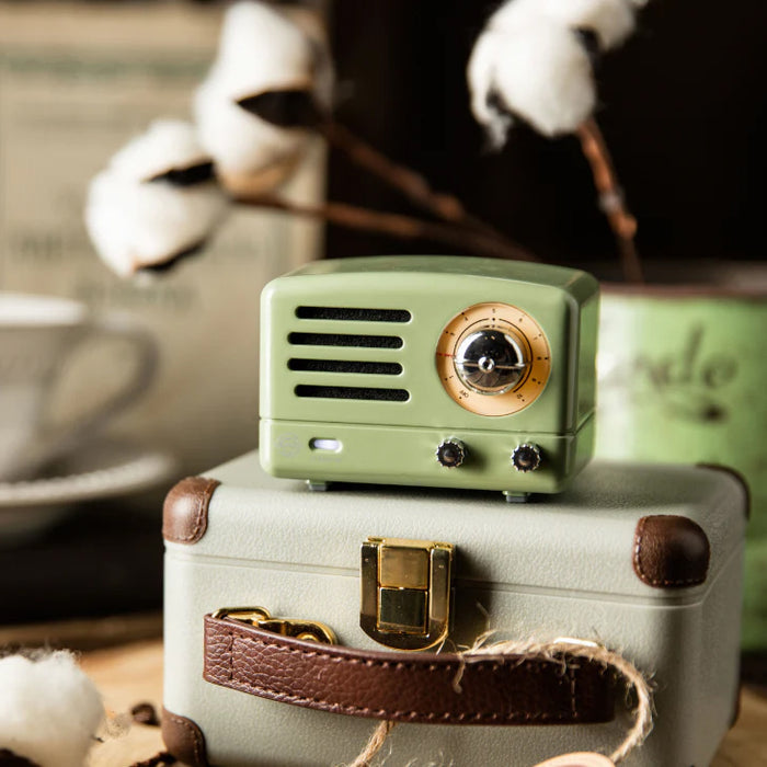Small green radio on a vintage suitcase and coffee cups in the background