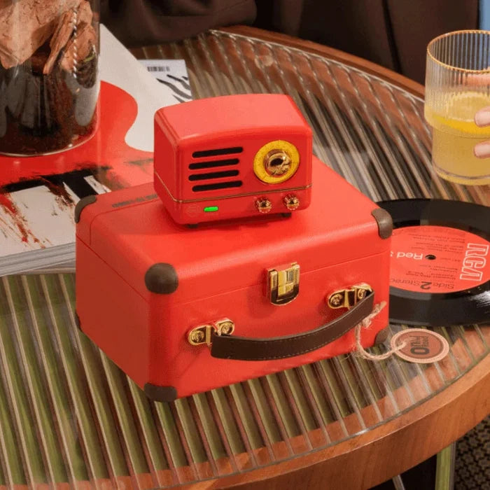 Red vintage-style radio on a suitcase with a person holding a glass of orange juice.