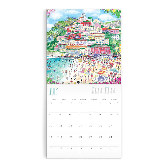 A vertical wall calendar page featuring a colorful watercolor illustration of a coastal hillside town with beachgoers and a large July calendar grid below.