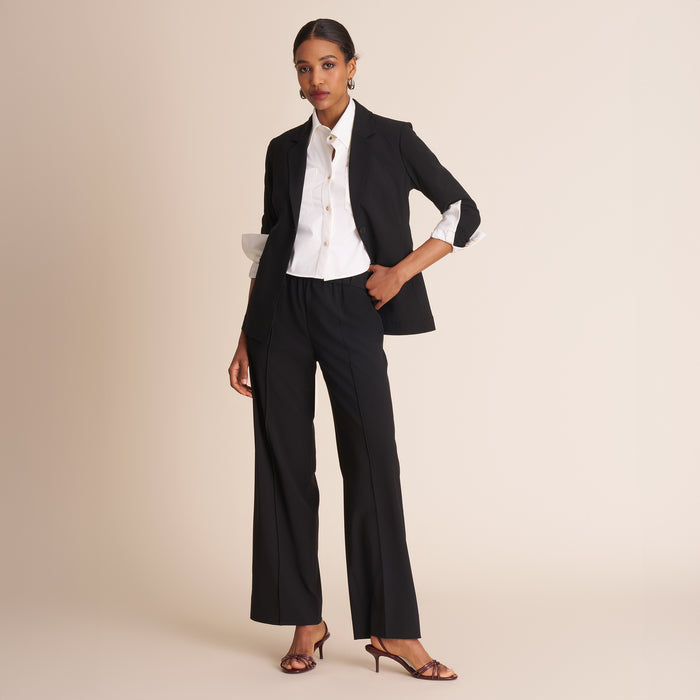 Woman wearing a black suit with a white shirt on a beige background