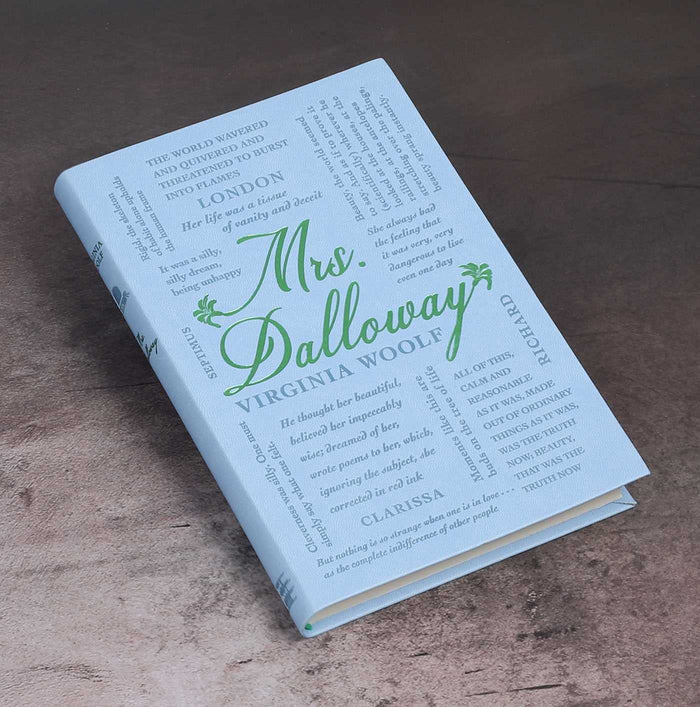 The book 'Mrs. Dalloway' by Virginia Woolf, featuring a pale blue cover with green and gray typography, displayed on a textured brown surface.