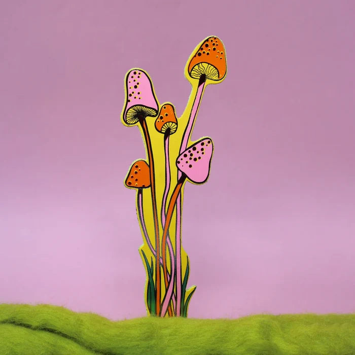 A yellow with orange and pink details bookmark shaped as a mushrooms against a solid light light purple background.