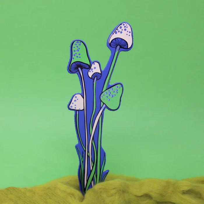 A royal blue with green and pink details bookmark shaped as a mushrooms against a solid light green background.