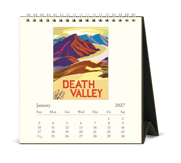 A spiral-bound desk calendar showing the January 2027 page, featuring a colorful Death Valley landscape illustration on the front cover.