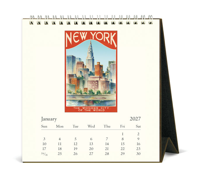A spiral-bound 2027 desk calendar showing January, with a vintage-style New York City skyline illustration on the page. The calendar is displayed open on a white background with a black support stand.
