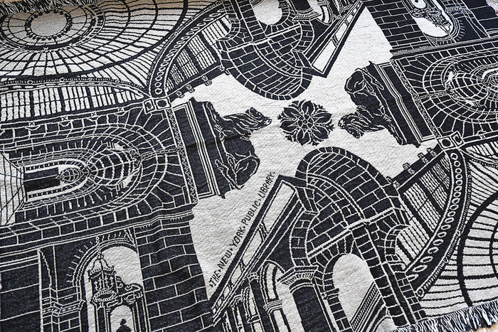 Close-up of a black and beige patterned fabric with architectural designs and 'The New York Public Library' text.