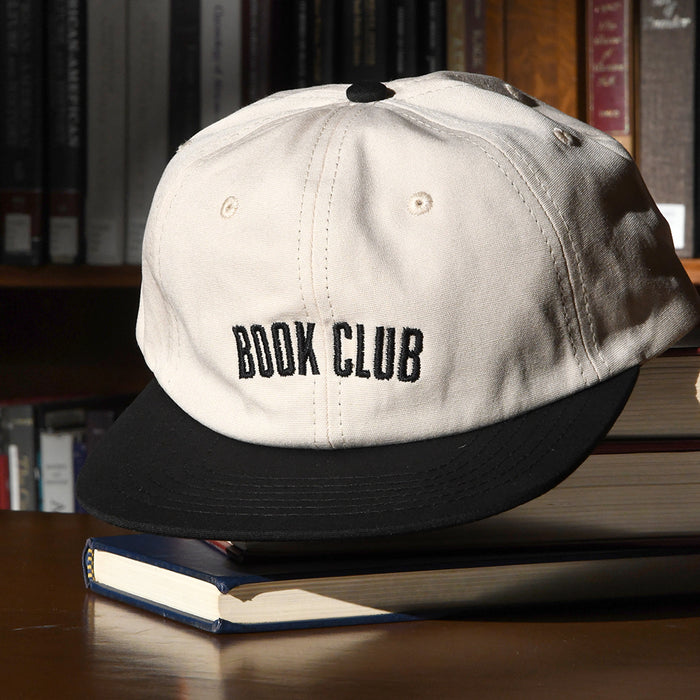 Off-white and black cap with 'BOOK CLUB' text .