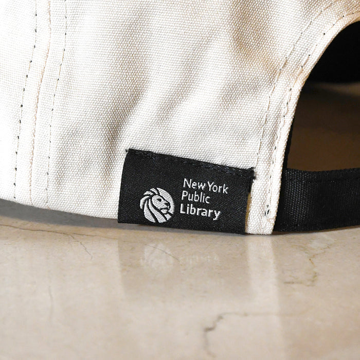 Close-up of a cap with a New York Public Library logo on a beige background