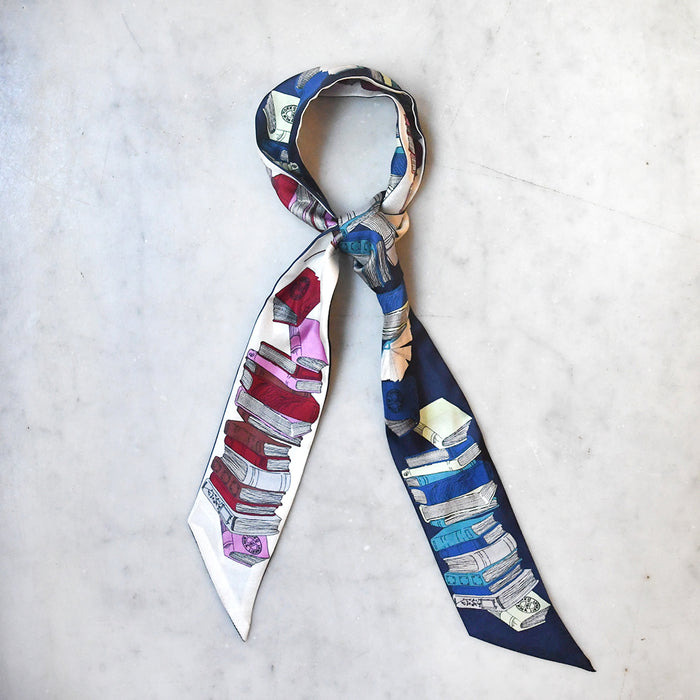 Double-sided blue and pink twilly scarf featuring book stacks with an oval NYPL stamp.