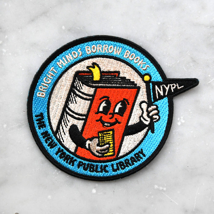 Colorful patch with an illustration of a book holding a library card and a mini pennant that reads NYPL. The text at the top reads 'Bright Minds Borrow Books' and the bottom reads: The New York Public Library.