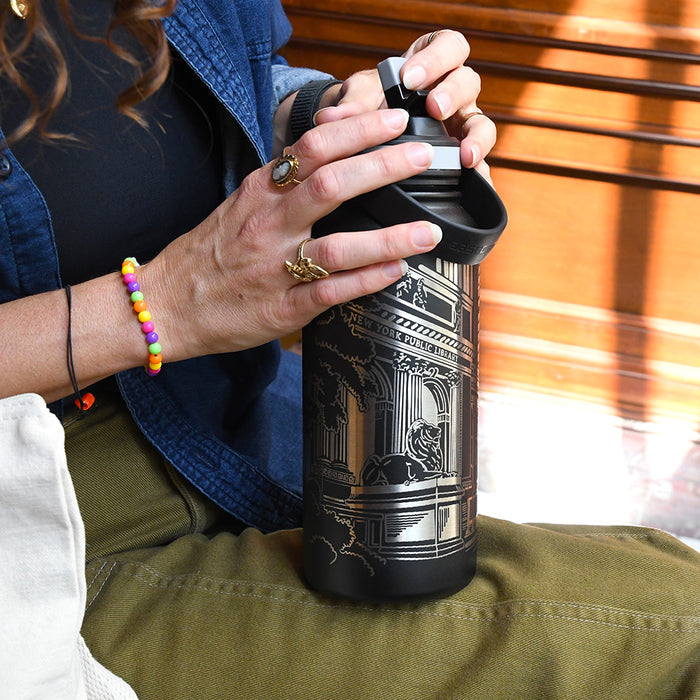 Person holding a black water bottle with silver decorative design of NYPL's flagship building.