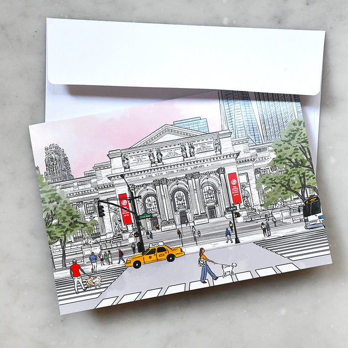 An illustrated greeting card featuring a colorful, detailed sketch of the New York Public Library main entrance with a yellow taxi and pedestrians in the foreground, shown with a plain white envelope.