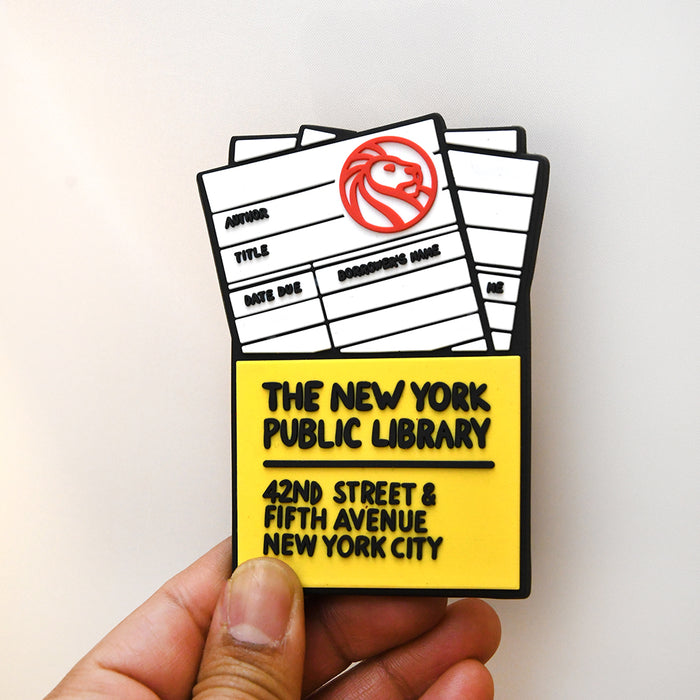 Rubber magnet simulating a NYPL library card. Text on yellow pouch reads: The New York Public Library. 42nd street & Fifth Avenue New York City.