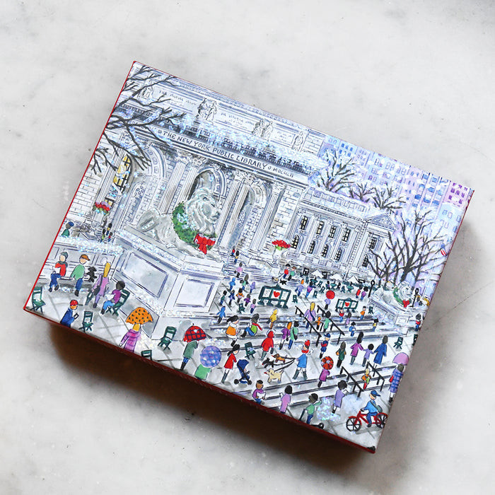 Box with a colorful illustration of the New York Public Library during the holidays scene on a marble surface.