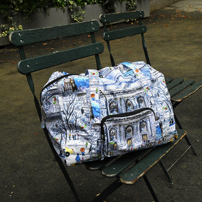 Foldable duffle bag featuring an illustration of the NYPL's flagship building during the winter season on a chair.