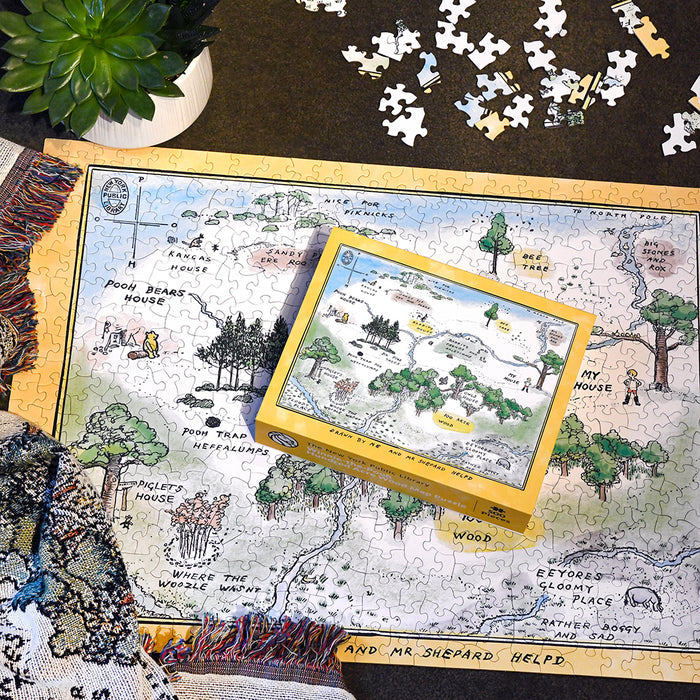 A yellow box for the Winnie-the-Pooh Hundred Acre Wood Map Puzzle rests on top of the fully completed 500-piece puzzle.