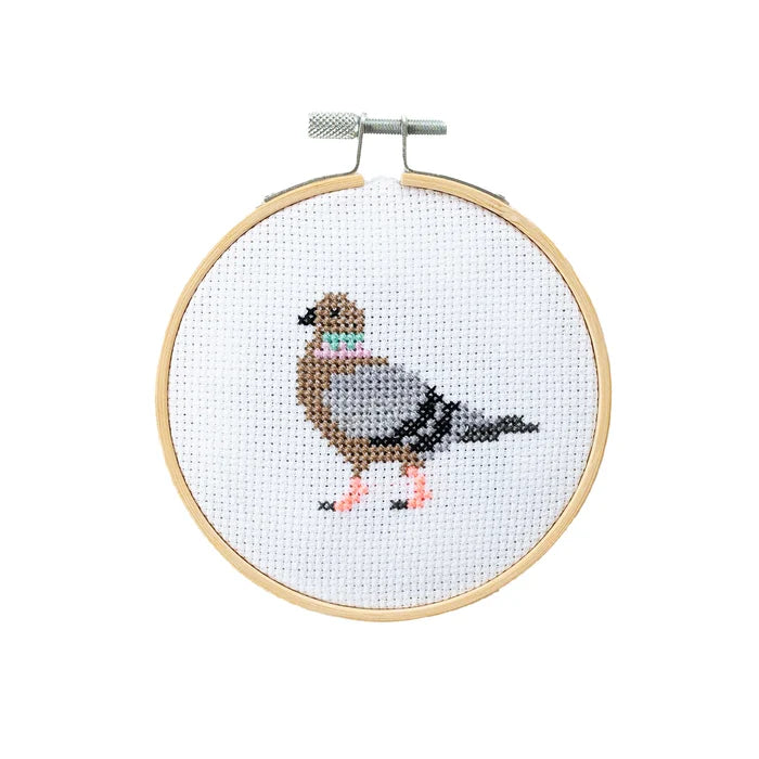 Cross-stitched bird design on a white background with a wooden hoop.