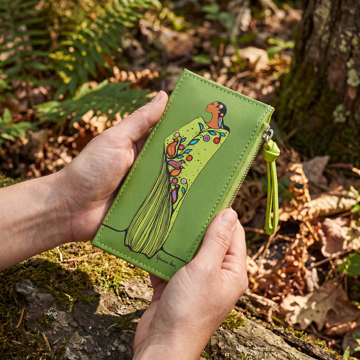 Green card holder with artistic design held in hands against a natural background