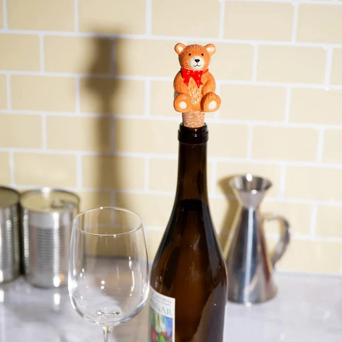 Wine bottle with a bear-shaped cork stopper on a kitchen counter.