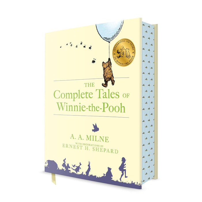 A cream hardcover edition of "The Complete Tales of Winnie-the-Pooh" by A.A. Milne, featuring a central illustration of Winnie-the-Pooh floating with a blue balloon and a silhouette of Hundred Acre Wood characters along the bottom.
