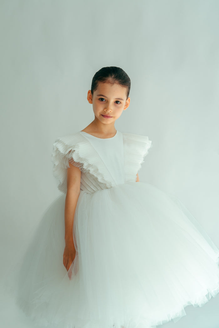 A young girl wearing a white, floral dress with voluminous sleeves and skirt